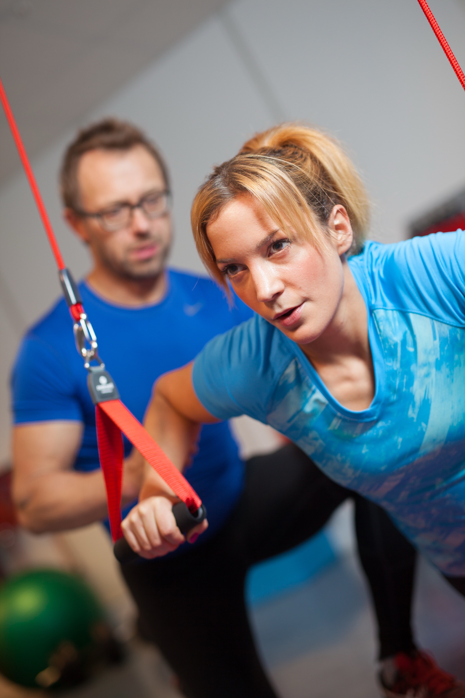 A coach guiding an athlete through a suspended Redcord exercise